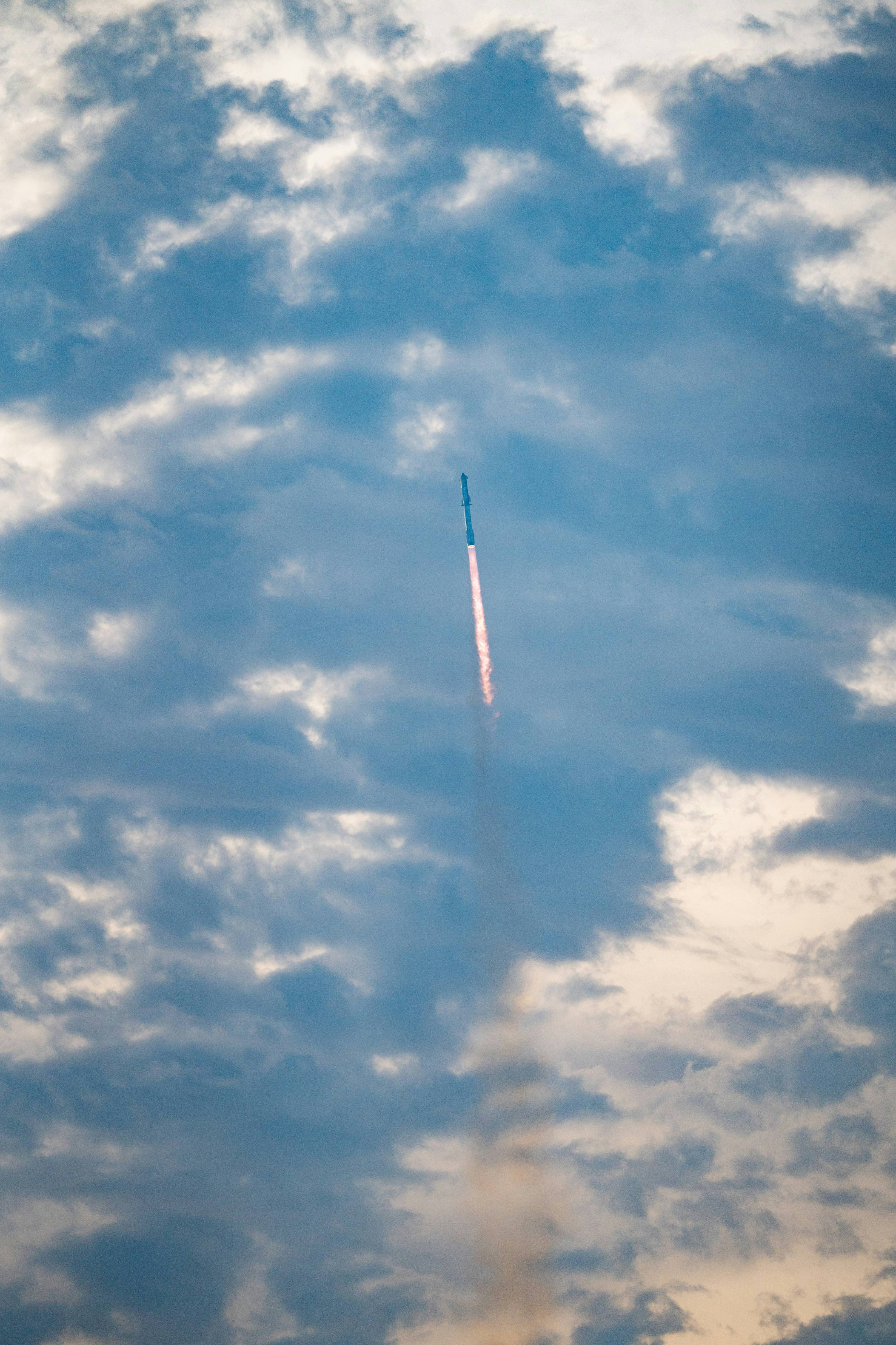 a jet flying through a cloudy blue sky