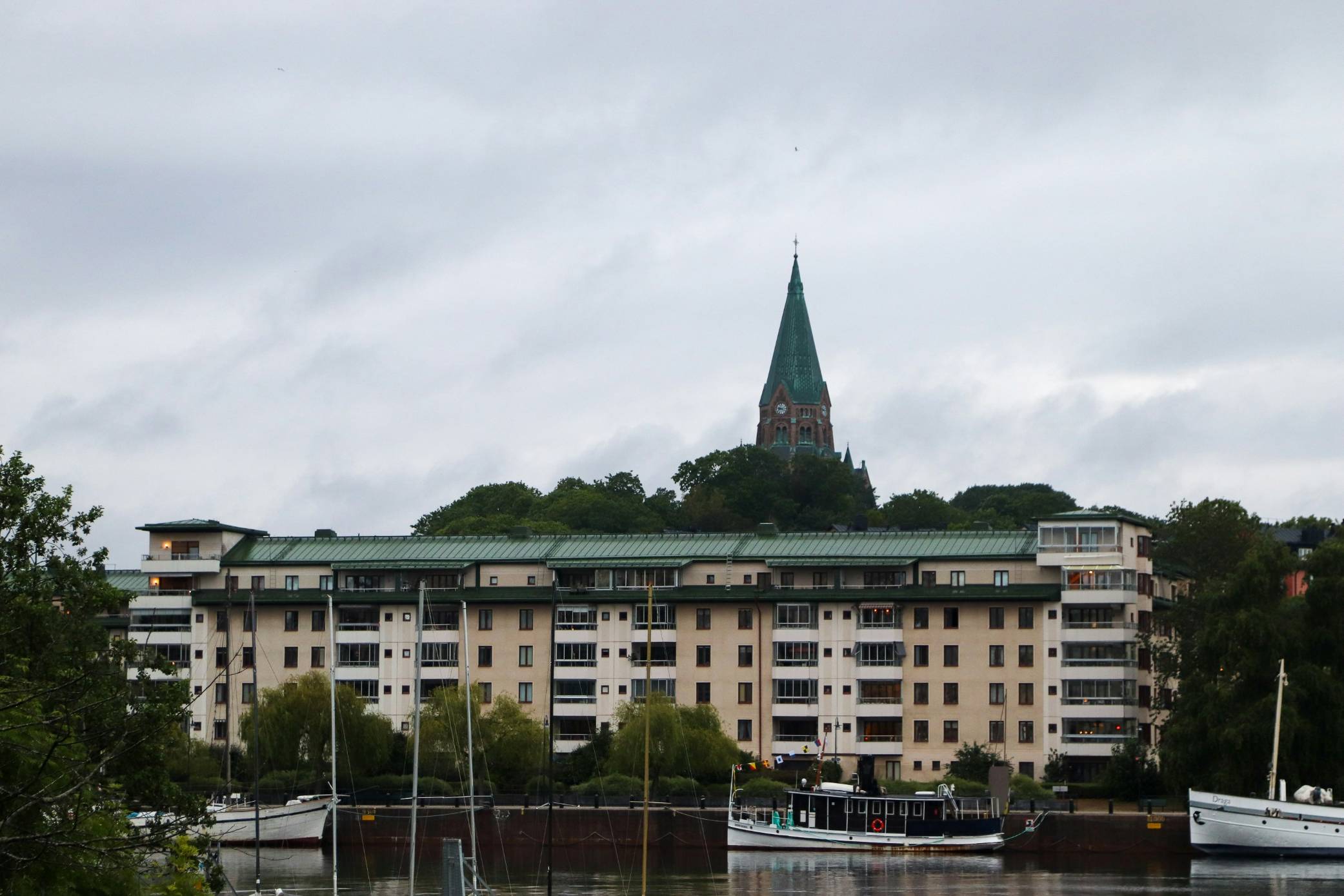 Building and church tower stand under overcast sky.