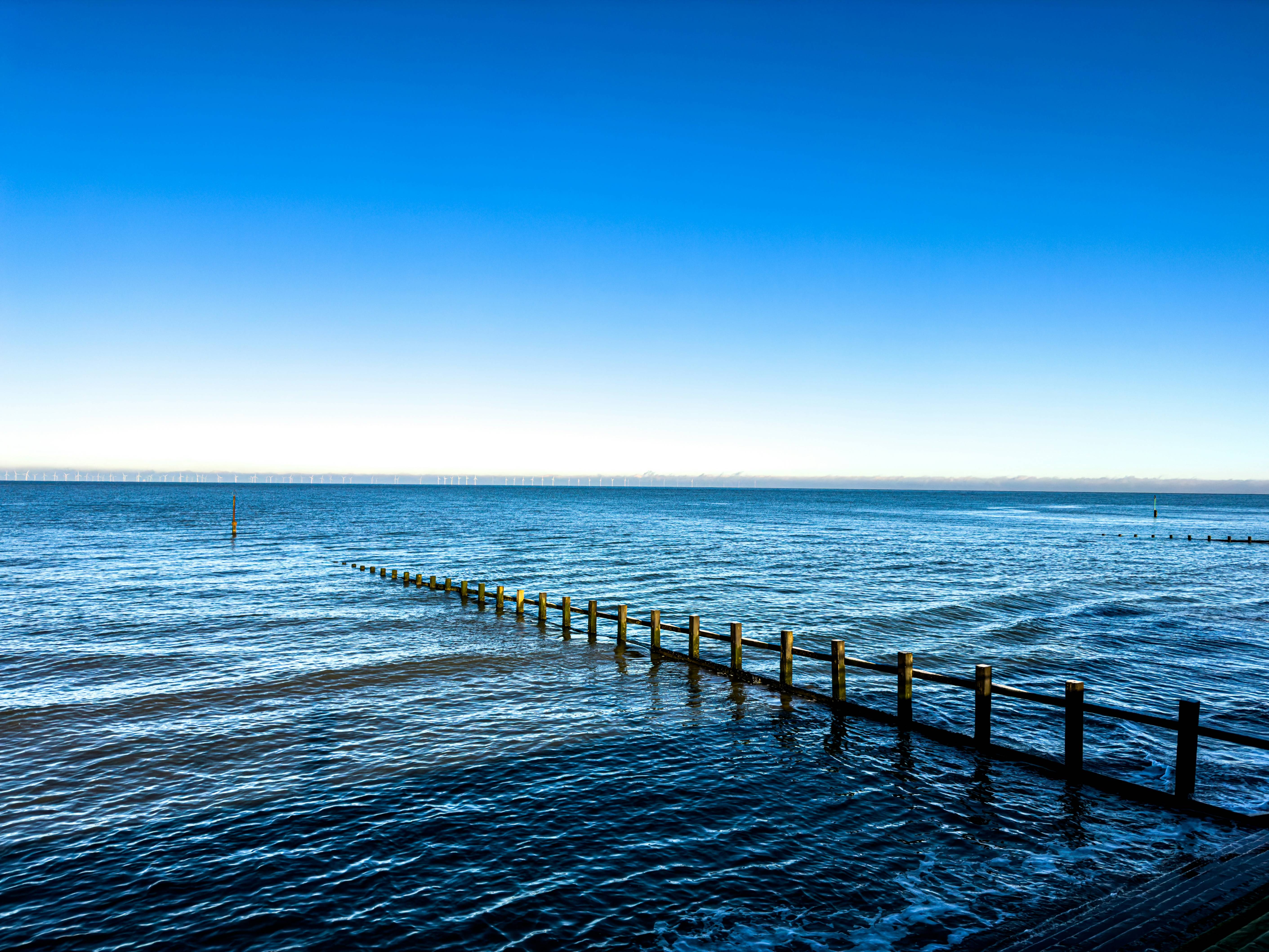a long wooden pier stretching out into the ocean