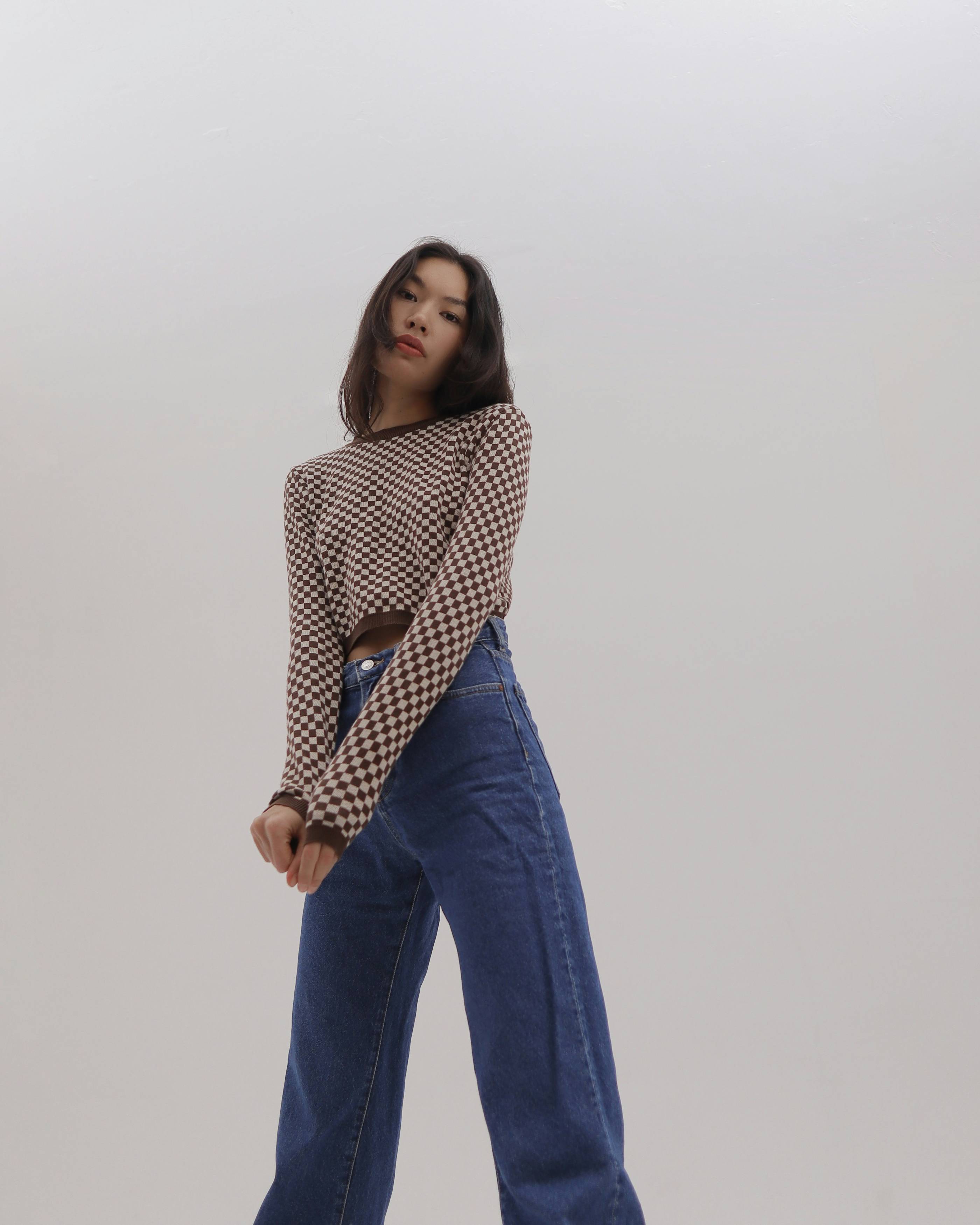 a woman in high rise jeans is posing for a picture
